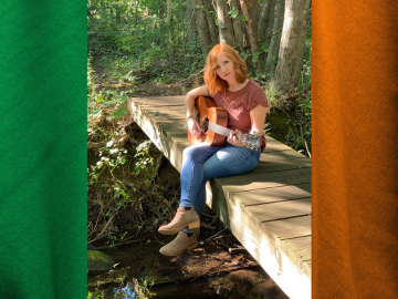 Photo of Liz McNicholl sitting on a small hiking bridge with the Irish flag in the background